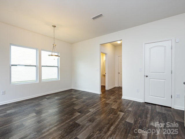 spare room with an inviting chandelier, visible vents, baseboards, and dark wood finished floors