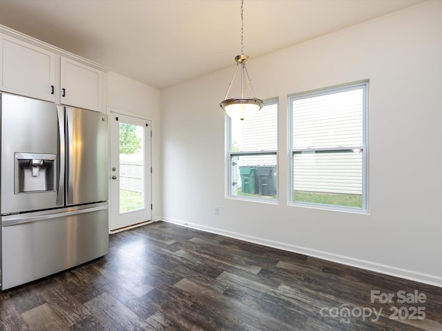 interior space with dark wood finished floors, hanging light fixtures, white cabinetry, stainless steel fridge, and baseboards