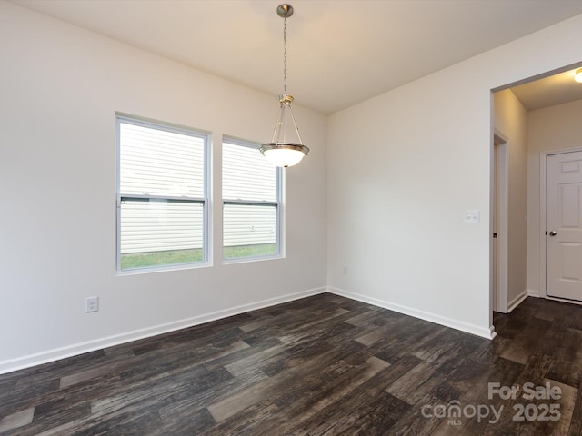 spare room featuring baseboards and dark wood-type flooring