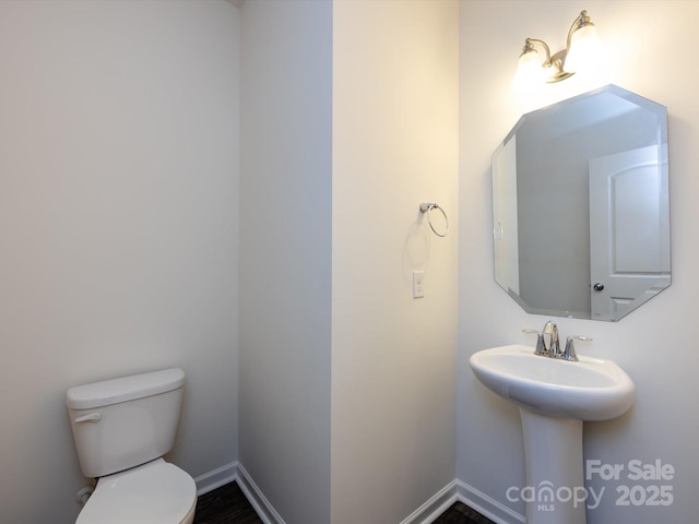 half bathroom featuring baseboards and toilet