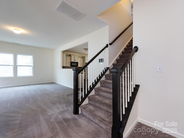 staircase featuring baseboards, visible vents, and carpet flooring