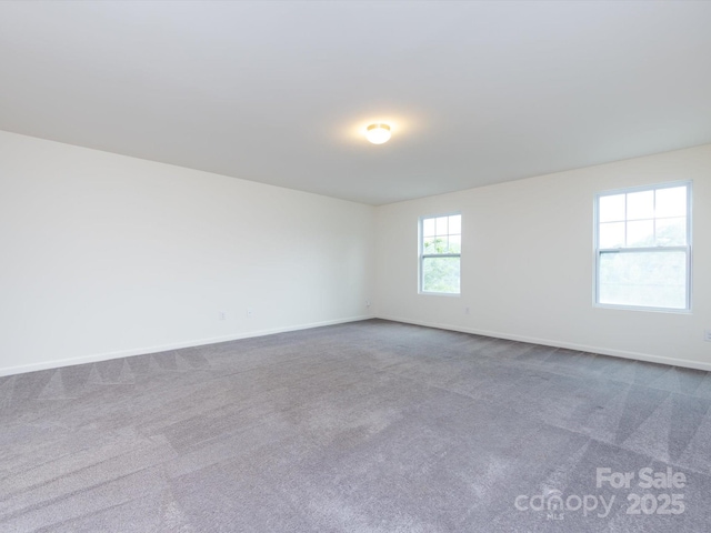 empty room with dark carpet and baseboards