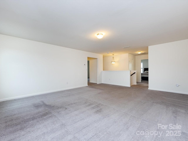 unfurnished living room featuring light colored carpet and baseboards