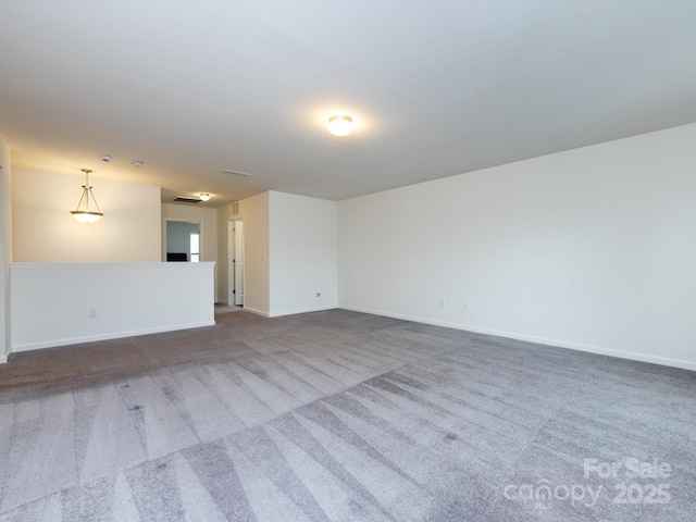 carpeted spare room featuring baseboards and visible vents