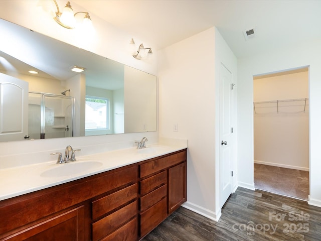 full bath featuring wood finished floors, visible vents, a shower stall, and a sink