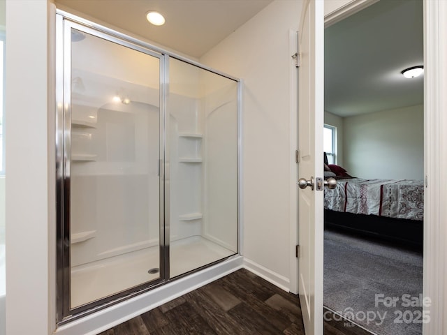 bathroom with a stall shower, wood finished floors, connected bathroom, and baseboards