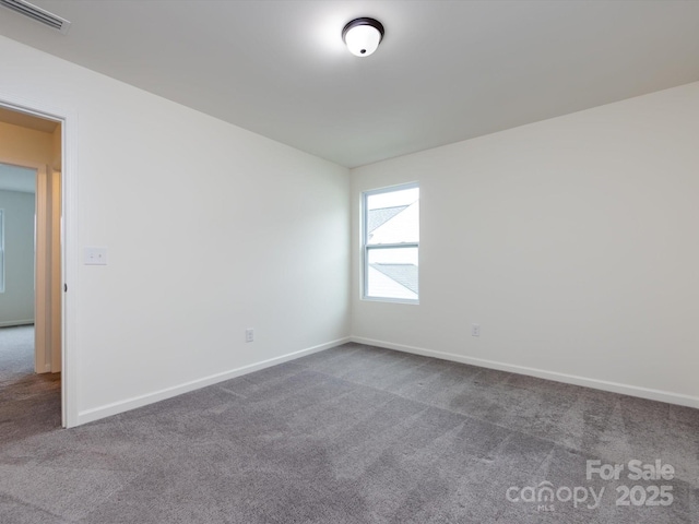 unfurnished room featuring visible vents, dark colored carpet, and baseboards