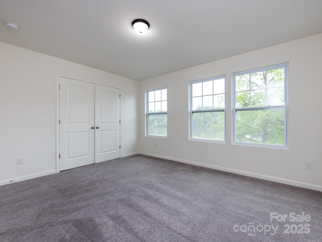 unfurnished bedroom featuring dark colored carpet, a closet, and baseboards