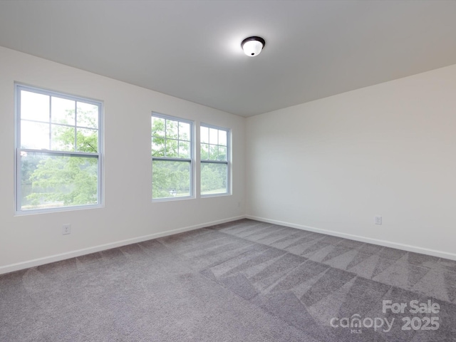 carpeted spare room featuring baseboards