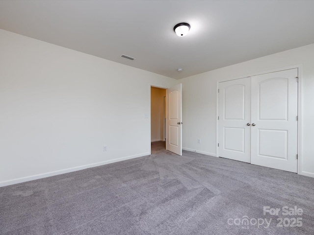 unfurnished bedroom with a closet, visible vents, carpet, and baseboards