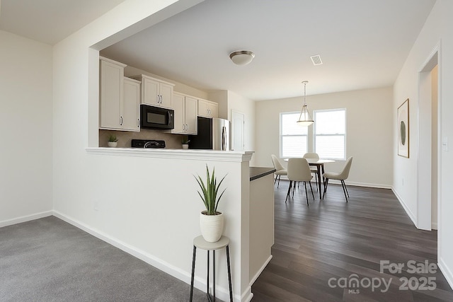 1523 Loropetalum Rd, Charlotte, NC 28215 - kitchen with black microwave, freestanding refrigerator, white cabinetry, visible vents, and pendant lighting