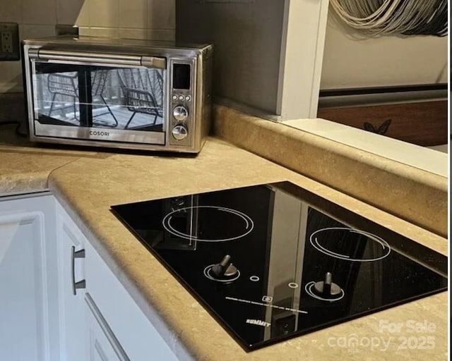 160 Whitney Blvd, Lake Lure, NC 28746 - interior details featuring light countertops, white cabinets, stainless steel microwave, and black electric stovetop