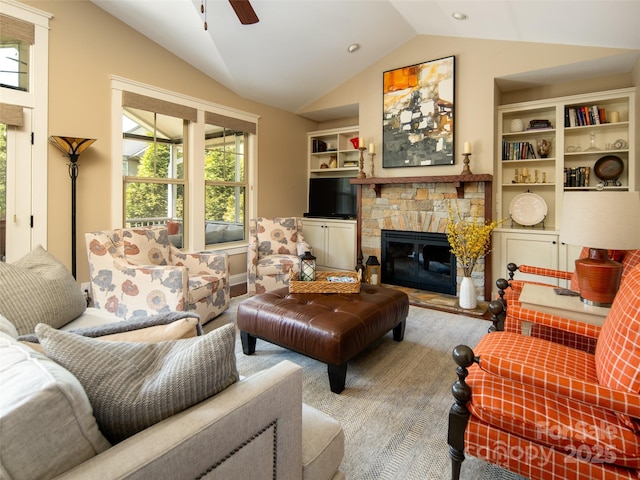 living area featuring a ceiling fan, vaulted ceiling, a stone fireplace, and a wealth of natural light