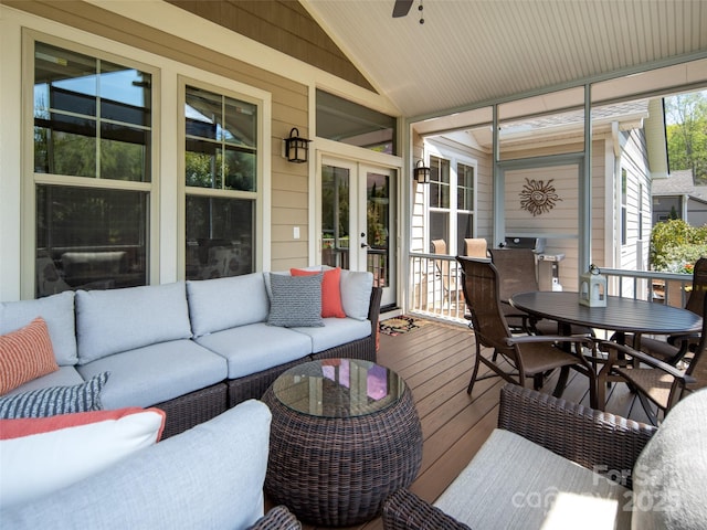 sunroom featuring french doors, a ceiling fan, outdoor dining space, and an outdoor living space