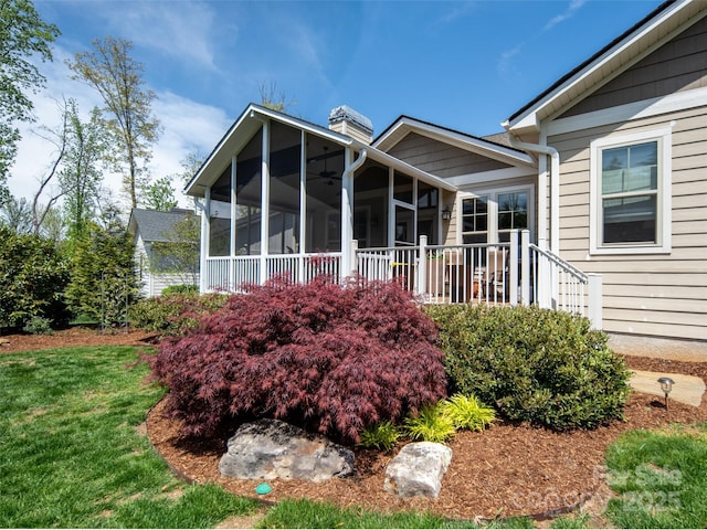 exterior space featuring a lawn, a ceiling fan, and a chimney