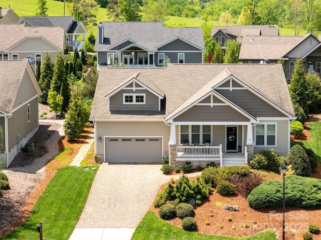 view of front of home with a residential view, covered porch, a shingled roof, and driveway