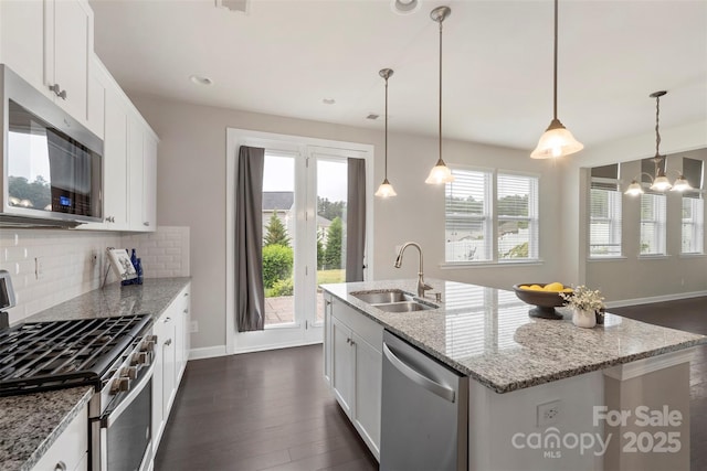 kitchen with plenty of natural light, stainless steel appliances, backsplash, a sink, and baseboards