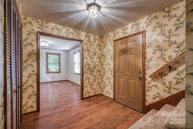 entrance foyer featuring baseboards, wallpapered walls, and wood finished floors