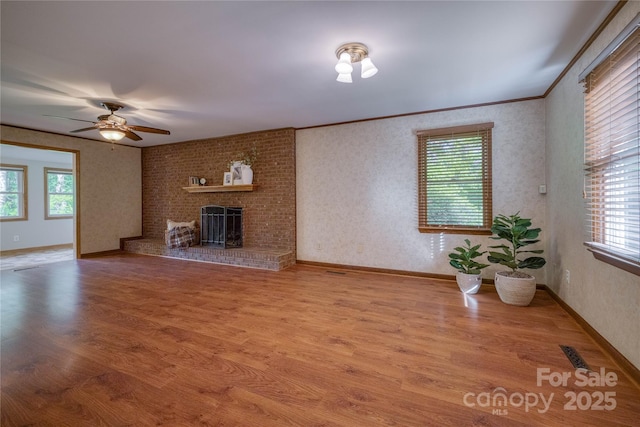 unfurnished living room featuring visible vents, wood finished floors, a fireplace, baseboards, and a ceiling fan