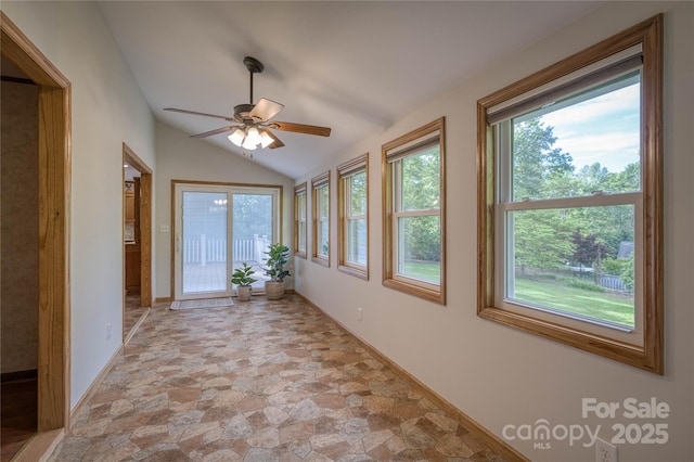unfurnished sunroom featuring baseboards, stone finish flooring, and lofted ceiling