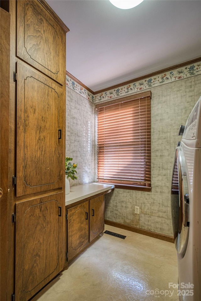 clothes washing area featuring crown molding, visible vents, washing machine and dryer, baseboards, and cabinet space