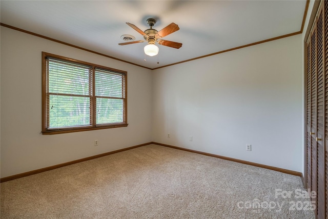 carpeted spare room featuring baseboards, ornamental molding, and a ceiling fan