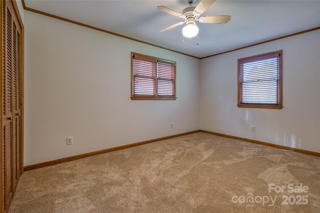 spare room with carpet flooring, a ceiling fan, baseboards, and ornamental molding