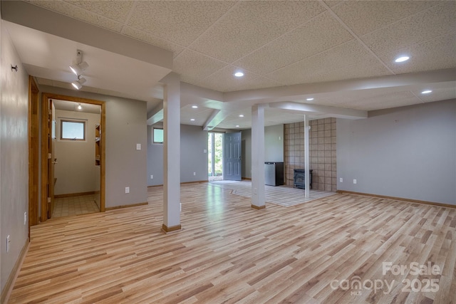 unfurnished living room with recessed lighting, baseboards, a drop ceiling, and light wood-style flooring