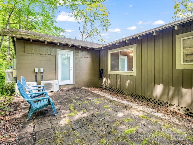 back of property featuring board and batten siding, ac unit, a shingled roof, and a patio area