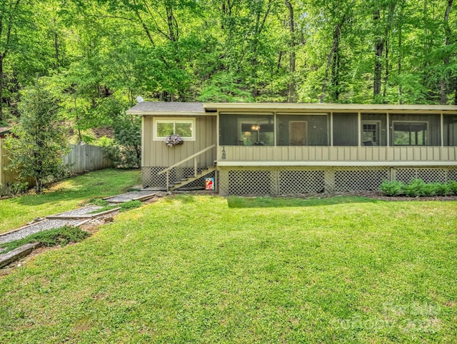 view of front of house featuring fence, a sunroom, and a front lawn