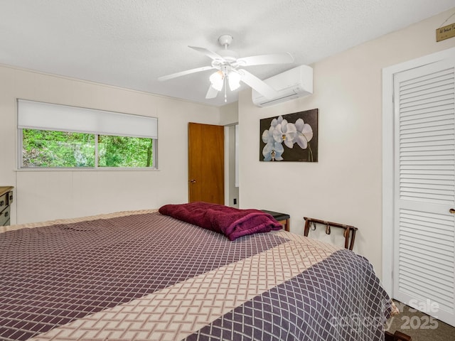 bedroom with an AC wall unit, ceiling fan, a textured ceiling, and a closet
