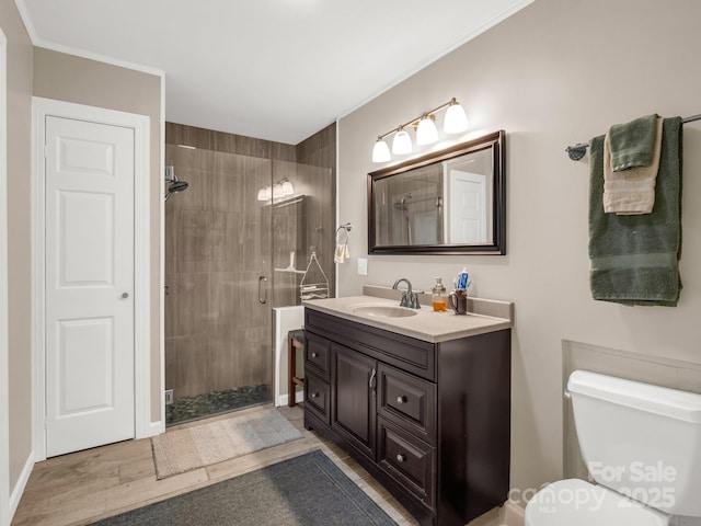 bathroom with vanity, a stall shower, toilet, and wood finished floors