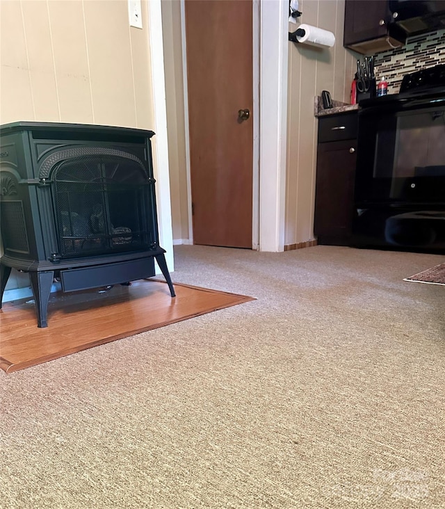 details featuring carpet flooring, stove, decorative backsplash, and a wood stove