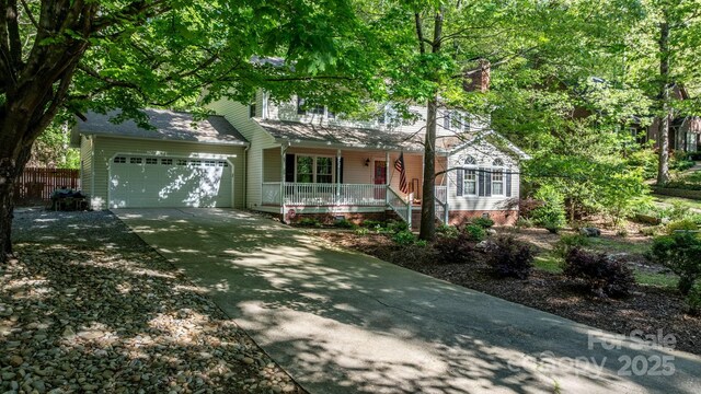 view of front of property with covered porch, fence, driveway, and a garage