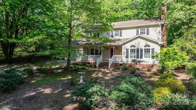 colonial house with crawl space, covered porch, and a chimney