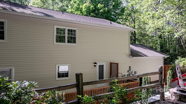 exterior space featuring fence and a shingled roof