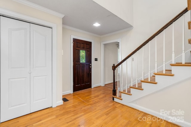 foyer with crown molding, baseboards, stairway, and wood finished floors