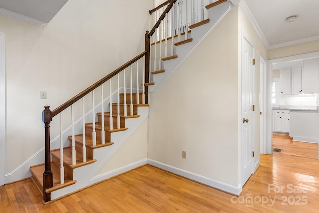stairway with baseboards, ornamental molding, and wood finished floors