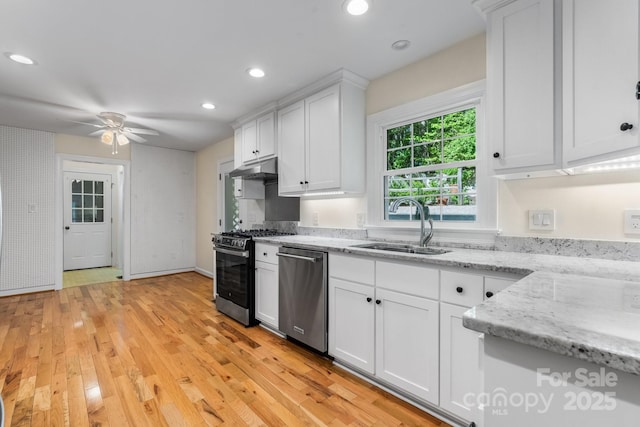 kitchen featuring a ceiling fan, a sink, white cabinets, stainless steel appliances, and light wood-style flooring