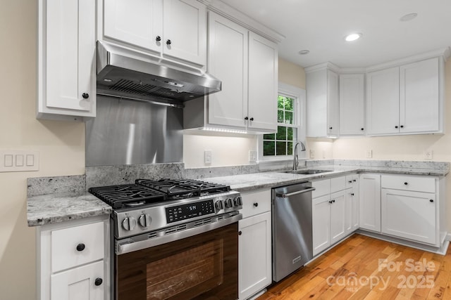 kitchen with a sink, light wood finished floors, stainless steel appliances, white cabinetry, and under cabinet range hood
