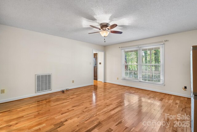 unfurnished room featuring a ceiling fan, a textured ceiling, visible vents, and light wood-style floors