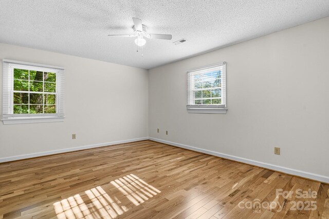 unfurnished room featuring a ceiling fan, a textured ceiling, visible vents, wood finished floors, and baseboards