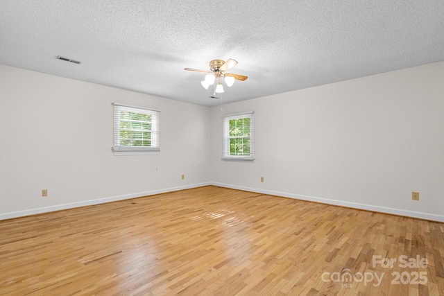 spare room with light wood-type flooring, baseboards, ceiling fan, and visible vents