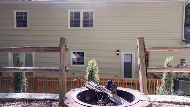 rear view of property featuring a fire pit, central air condition unit, and a deck