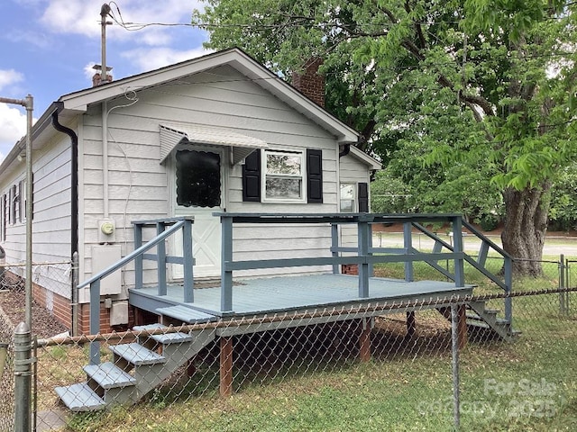 rear view of property with a wooden deck, a chimney, and fence