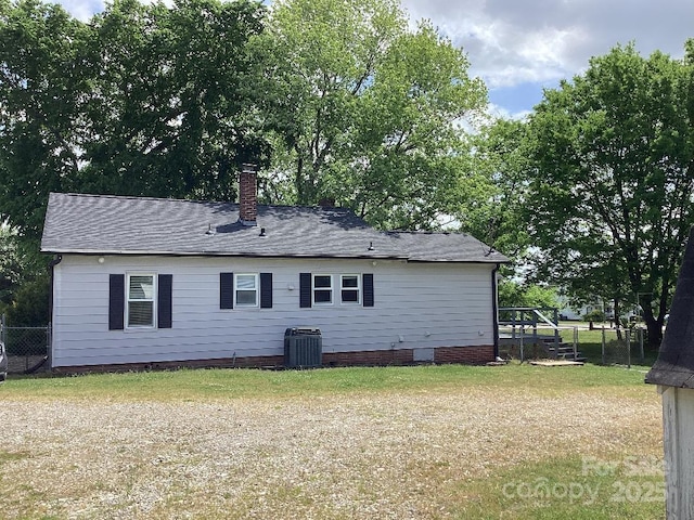back of property featuring central air condition unit, fence, a chimney, and a shingled roof
