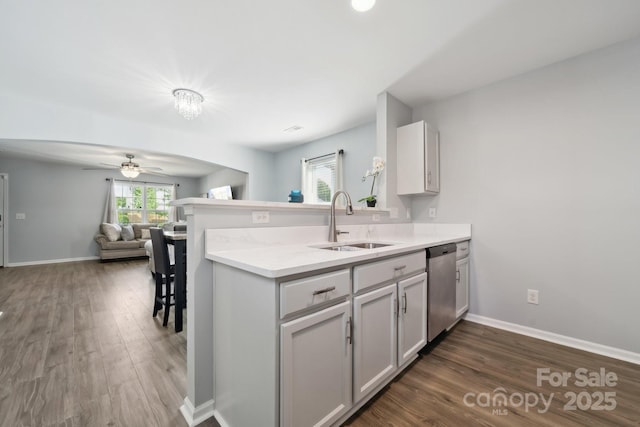 kitchen with a sink, ceiling fan, a peninsula, stainless steel dishwasher, and open floor plan