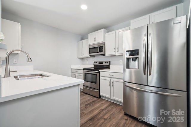 kitchen featuring white cabinets, a sink, appliances with stainless steel finishes, light countertops, and dark wood-type flooring