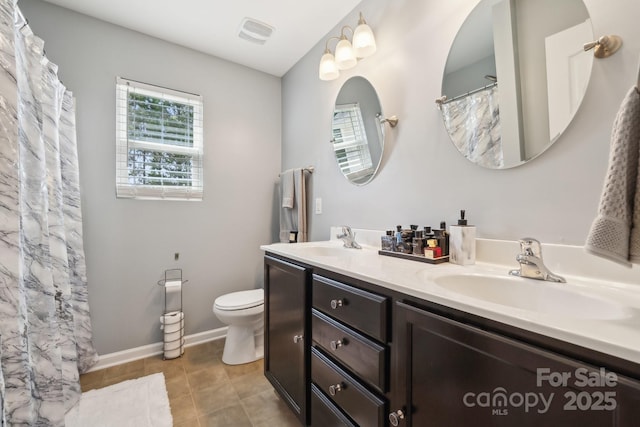 bathroom with toilet, double vanity, a sink, and visible vents