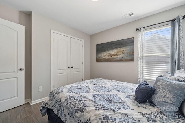 bedroom with a closet, visible vents, wood finished floors, and baseboards